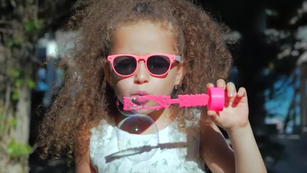 Happy Little Girl playing outdoor, blowing soap bubbles, having fun on backyard. Nature. Beautiful Child in Park. — Stock Video