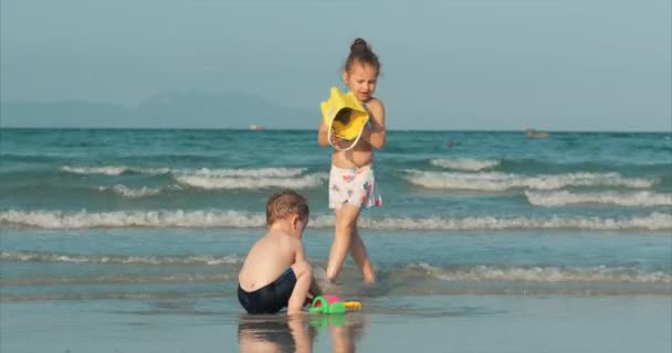 Šťastné a bezstarostné děti si hrají u moře s pískem. Děti si hrají, bratr a sestra si hrají u moře. Šťastné dětství. — Stock video