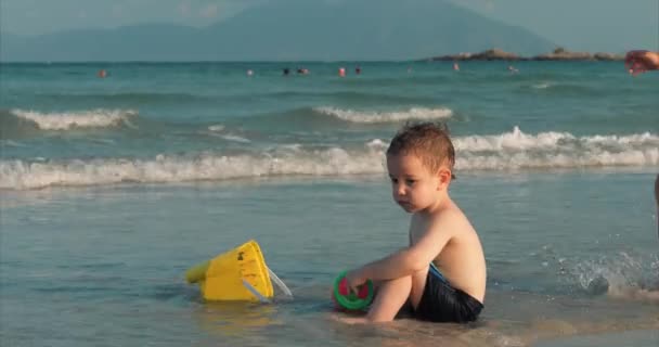 Crianças felizes e despreocupadas brincando junto ao mar com areia. Crianças brincando, irmão e irmã brincam à beira-mar. Infância feliz . — Vídeo de Stock