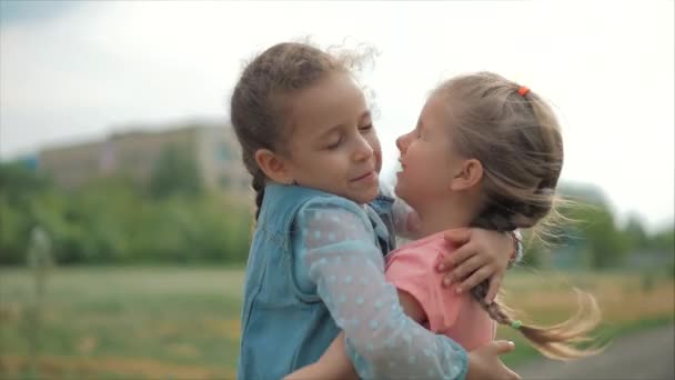 Dos hermanas sonrientes, rizadas y lindas se abrazan con fuerza. Feliz infancia, emociones positivas, sentimientos verdaderos . — Vídeos de Stock