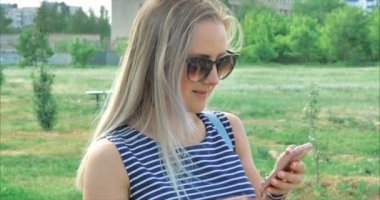 Telefon cihazına metin mesajları yazarak gözlük ile mutlu genç kadın.