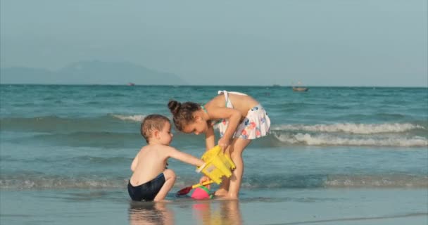 Crianças felizes e despreocupadas brincando junto ao mar com areia. Crianças brincando, irmão e irmã brincam à beira-mar. Infância feliz . — Vídeo de Stock