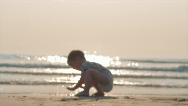 Silueta kojenů chůze po mokrém písku podél tropické pláže na pozadí tropického oceánu. Koncept: děti, šťastné dětství, léto, dítě, dovolená. Měkké zaměření. — Stock video