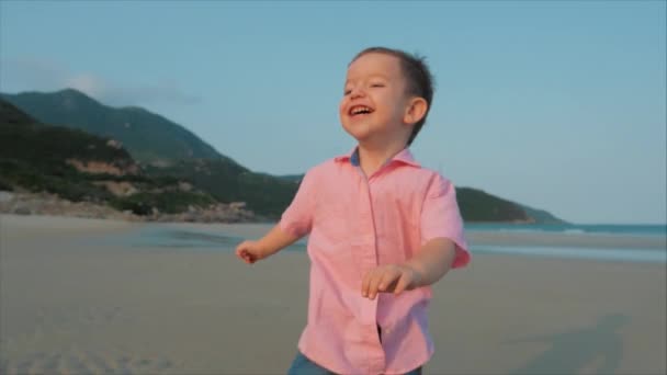 Šťastný kluk, co běží po pláži. Silueta kojenů chůze po mokrém písku podél tropické pláže na pozadí tropického oceánu. Koncept: děti, šťastné dětství, léto, dítě. měkké zaměření