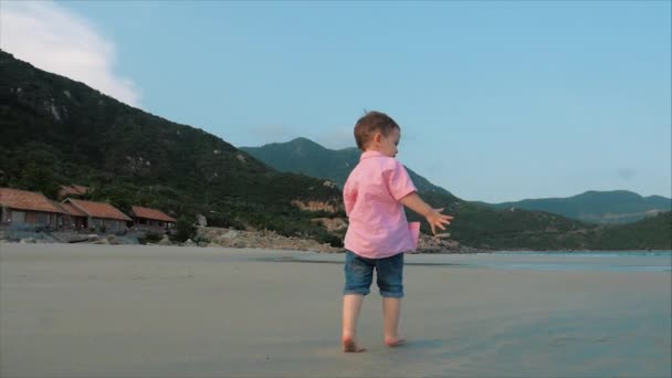 Ragazzo felice che corre lungo la spiaggia.Silhouette dei piedi dei bambini che camminano sulla sabbia bagnata lungo una spiaggia tropicale su uno sfondo oceanico tropicale.Concetto: Bambini, Infanzia felice, Estate, Bambino. — Video Stock