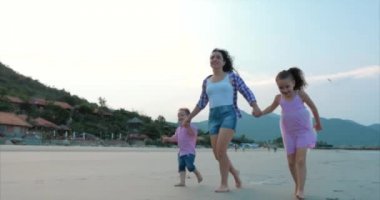 Genç aile, anne ve çocuk sahil boyunca yürüyor. Mutlu aile deniz kıyısında yürüyüş.
