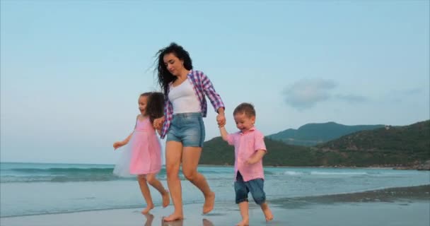 Jong gezin, moeder en kinderen lopen langs de kust. Lopen aan zee en gelukkige familie. — Stockvideo