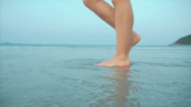 Bir tropikal plaj güzel sahne Sunset Ocean Beach yürüyüş bir kadın üzerinde. Yakın çekim kadın bacaklar Avrupa güzel esmer, plaj boyunca yürüyüş, yavaş hareket.