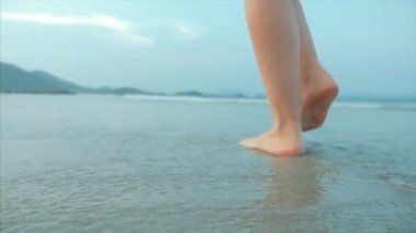 Bir tropikal plaj güzel sahne Sunset Ocean Beach yürüyüş bir kadın üzerinde. Yakın çekim kadın bacaklar Avrupa güzel esmer, plaj boyunca yürüyüş, yavaş hareket.