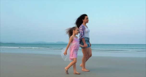 젊은 가족, 어머니와 딸이 해안을 따라 걷고 있습니다. 바다 해안을 걷는 행복한 가족. — 비디오