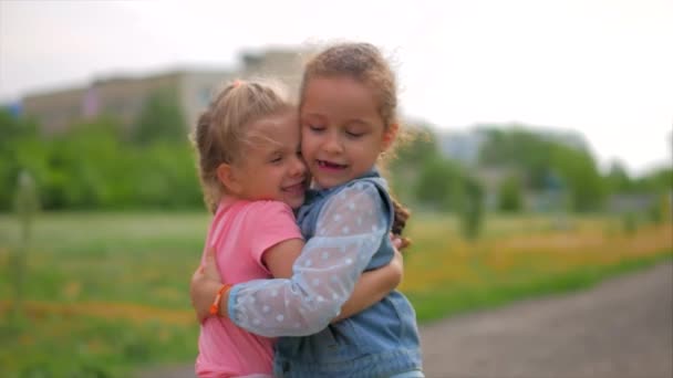 Dos hermanas sonrientes, rizadas y lindas se abrazan con fuerza. Feliz infancia, emociones positivas, sentimientos verdaderos . — Vídeo de stock