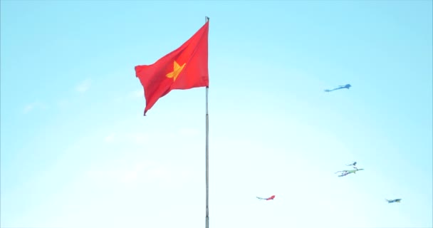 Bandeira Nacional do Vietnã paira contra o céu azul e pipas voadoras. Vídeo 4K da bandeira do Vietname com bandeira. A bandeira nacional é vermelha com uma grande estrela dourada . — Vídeo de Stock