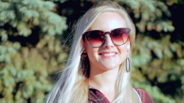 Güneş Gözlüğü Genç Kadın veya Neşeli Kız Kamera Looking ile Avrupa Güzel Sevimli Blonde Close-Up Portre, Rüzgar Rüzgar Üfleme , Yavaş Hareket.