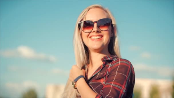 Nahaufnahme Porträt der schönen, süßen Blondine mit Sonnenbrille, junge Frau oder fröhliches Mädchen, das in die Kamera schaut, Wind weht Haare im Wind, Zeitlupe. — Stockvideo