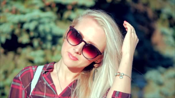 Blízký portrét Evropské krásné rozkošné blondýny s Sunglass mladou ženou nebo veselou dívkou, která se dívá do kamery, foukající větrné vlasy vítr, pomalý pohyb. — Stock video