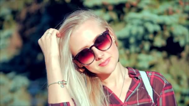 Gros plan Portrait d'une belle blonde mignonne européenne avec des lunettes de soleil Jeune femme ou fille joyeuse regardant dans la caméra, Vent soufflant Cheveux le vent, Mouvement lent . — Video