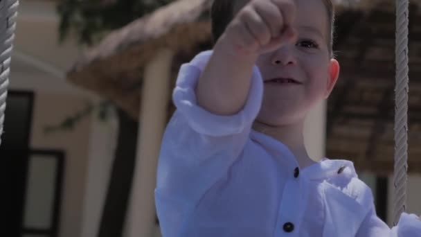 Passeio de criança feliz em um balanço. Infância feliz, férias de verão. Happy Little Boy sorrindo cavalgando no balanço . — Vídeo de Stock