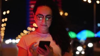 Pretty Woman beyaz bir t-shirt ve gözlük sokakta duruyor, kredi kartı ve akıllı telefon, online alışveriş teknolojisi ile online ödemeler yapar. Kredi kartı ve cep telefonu ile satın alma için ödeme.