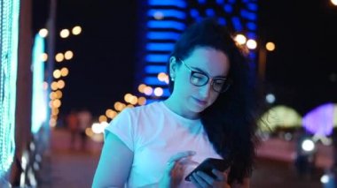 Pretty Woman beyaz bir t-shirt ve gözlük sokakta duruyor, kredi kartı ve akıllı telefon, online alışveriş teknolojisi ile online ödemeler yapar. Kredi kartı ve cep telefonu ile satın alma için ödeme.