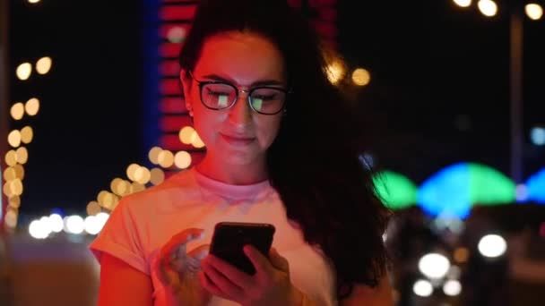 Jolie femme se tient dans la rue dans un t-shirt blanc et des lunettes, effectue des paiements en ligne par carte de crédit et smartphone, la technologie d'achat en ligne. Paiement par carte de crédit et téléphone portable . — Video