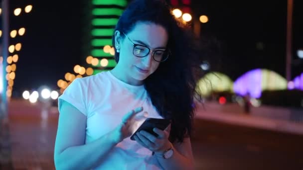 Jolie femme se tient dans la rue dans un t-shirt blanc et des lunettes, effectue des paiements en ligne par carte de crédit et smartphone, la technologie d'achat en ligne. Paiement par carte de crédit et téléphone portable . — Video