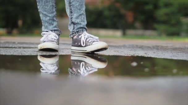 Niños de bajo ángulo, primer plano, irreconocibles corriendo a través de charcos el día de verano después de la lluvia. Los niños despreocupados corren en charcos. Concepto de una infancia feliz . — Vídeo de stock