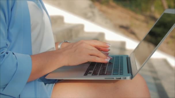 Business Lady arbetar på den bärbara datorn, attraktiv brunett i en blå kostym med en bärbar dator, attraktiv kvinna som arbetar på hennes dator på utomhus. — Stockvideo