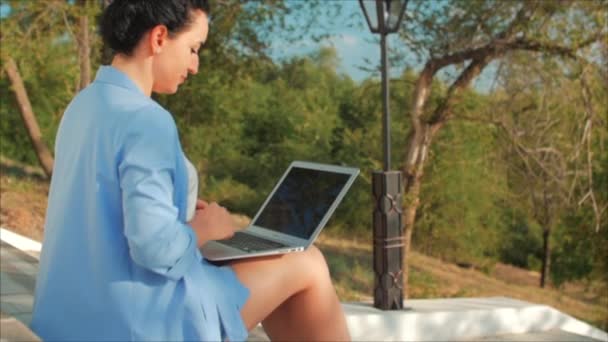 Femme d'affaires travaillant sur l'ordinateur portable, attrayant Brunette en costume bleu avec un ordinateur portable, femme attrayante travaillant sur son ordinateur en plein air . — Video