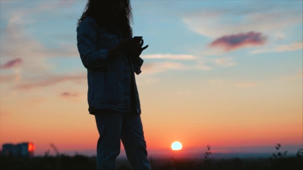 Beautiful Woman making heart shape with hands at sunset Girl holding up love symbol gesture with orange sun flare. — Stock Video