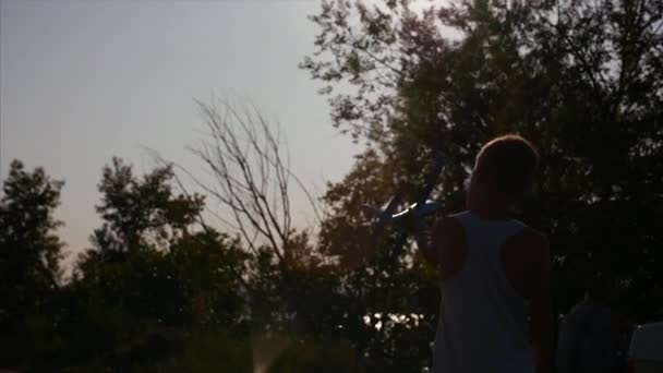 Gelukkig kind spelen. Gelukkige jongen met vliegtuig in handen van een zonsondergang achtergrond waarop. — Stockvideo