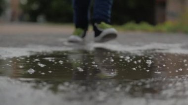 Düşük açı, yakın çekim, tanınmaz çocuklar yağmurdan sonra yaz günü su birikintileri arasında koşuyorlar. Tasasız çocuklar su birikintilerinde koşarlar. Mutlu bir çocukluk kavramı.