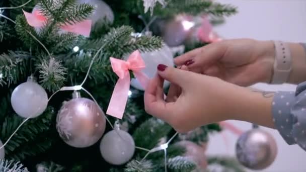 若い女性の手、お祭りのライトとクリスマスのお祝いクリスマス ツリーを飾るクリスマス ツリーに弓を普及. — ストック動画
