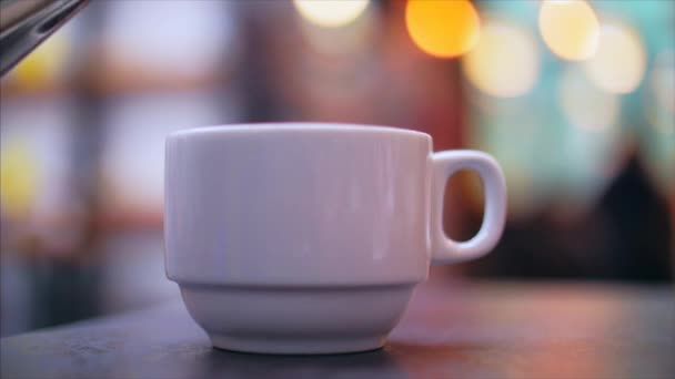 Τσάι από το βραστήρα χύνεται αργά σε ένα Κύπελλο πορσελάνης. — Αρχείο Βίντεο