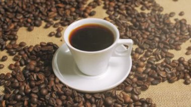 Kahve fincanı ve kahve çekirdekleri. Kavrulmuş fasulye ile masada buharlaşan kahve beyaz fincan. Stok görüntüleri.