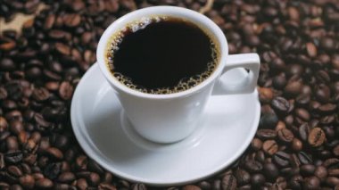 Kahve fincanı ve kahve çekirdekleri. Kavrulmuş fasulye ile masada buharlaşan kahve beyaz fincan. Stok görüntüleri.