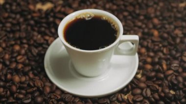 Kahve fincanı ve kahve çekirdekleri. Kavrulmuş fasulye ile masada buharlaşan kahve beyaz fincan. Stok görüntüleri.