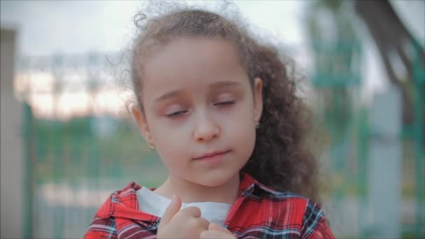 カメラを見て、日没に暖かい夏の日を楽しんで、ポートレートかわいい白人の小さな女の子をクローズアップ. — ストック動画