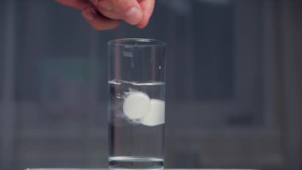 İki aspirin tableti bir bardak kristal berraklığında suya düşer, bir bardak suda gazlı kabarcıklar. Sağlık Kavramı. — Stok video
