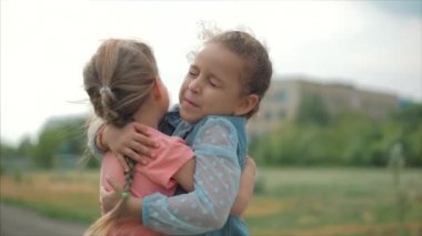 İki gülümseyen, kıvırcık, sevimli kız bebek kızları birbirine sıkıca sarılmak. Mutlu çocukluk, olumlu duygular, gerçek duygular.
