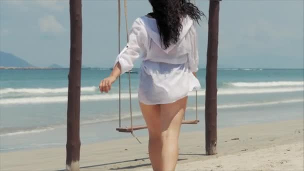 Joven hermosa mujer feliz disfrutando en un columpio en la playa contra el fondo del océano . — Vídeos de Stock