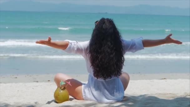 Joven o una chica alegre, tomando el sol en la playa, disfrutando del océano, bebiendo coco al sol, relajándose en una playa tropical. Concepto de viaje, olas del mar, descanso en el mar en el verano . — Vídeos de Stock