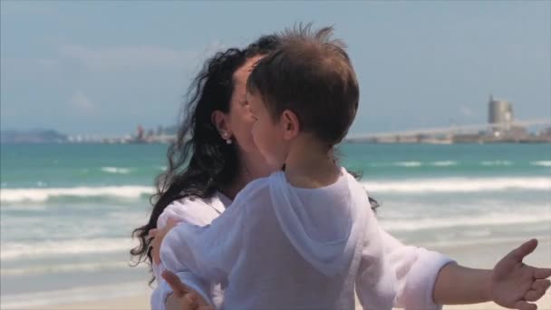 Feliz madre abrazando a su hijo en la costa. Cute Kid besa a su madre y gentilmente abraza. Concepto Mamá con un Niño al Aire Libre, Familia Feliz, Infancia Feliz, Niñito . — Vídeo de stock