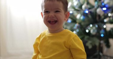 Komik küçük çocuk Noel ışıkları arka planda gülümseyen, sevimli bebek kameraya bakarak, gülümseyen, mutlu. Mutlu çocuk.