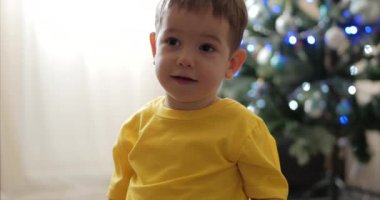 Komik küçük çocuk Noel ışıkları arka planda gülümseyen, sevimli bebek kameraya bakarak, gülümseyen, mutlu. Mutlu çocuk.