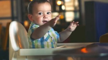 Çocuk bir çocuk sandalyesinde oturur, lapa yemeyi reddeder, kaprisli.