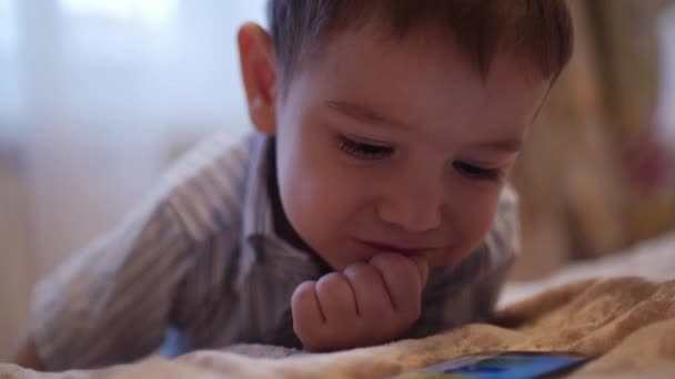 ЦУ счастливое лицо ребенка, маленький мальчик лежит на диване мобильный телефон, счастливое детство . — стоковое видео