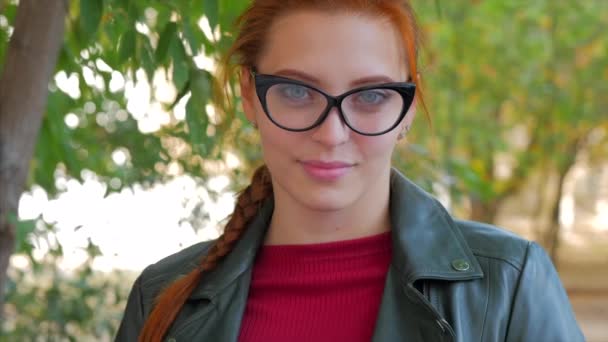 良い気分で長い赤い髪を持つ幸せな女性のメガネクローズアップ顔を持つ魅力的な笑顔の若い女性の肖像画、肯定的な感情. — ストック動画
