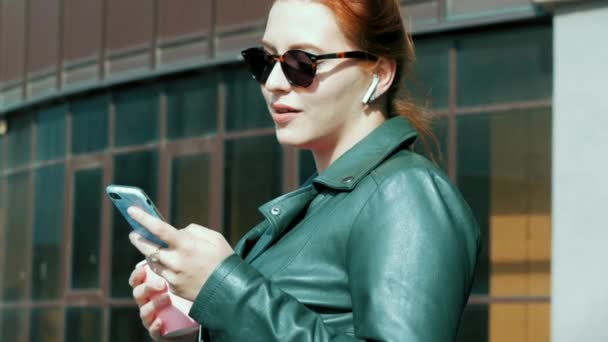 Young Woman Drinking Coffee on the Street, Typing Texting a Mobile Phone, While Walking in an Urban Setting. — Stock Video