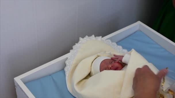 母親は出産後、生まれたばかりの赤ちゃんをベビーベッドに座る。生まれたばかりの赤ん坊は出産後ベッドに横たわり、カメラを見ている。病院の概念. — ストック動画