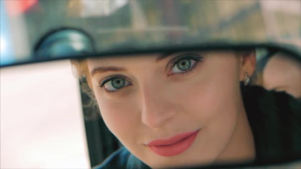 Jonge mooie vrouw op zoek in achteruitkijkspiegel schildert rode lippenstift lippen. Meisje vrouw bestuurder kijkt in de achteruitkijkspiegel. — Stockvideo